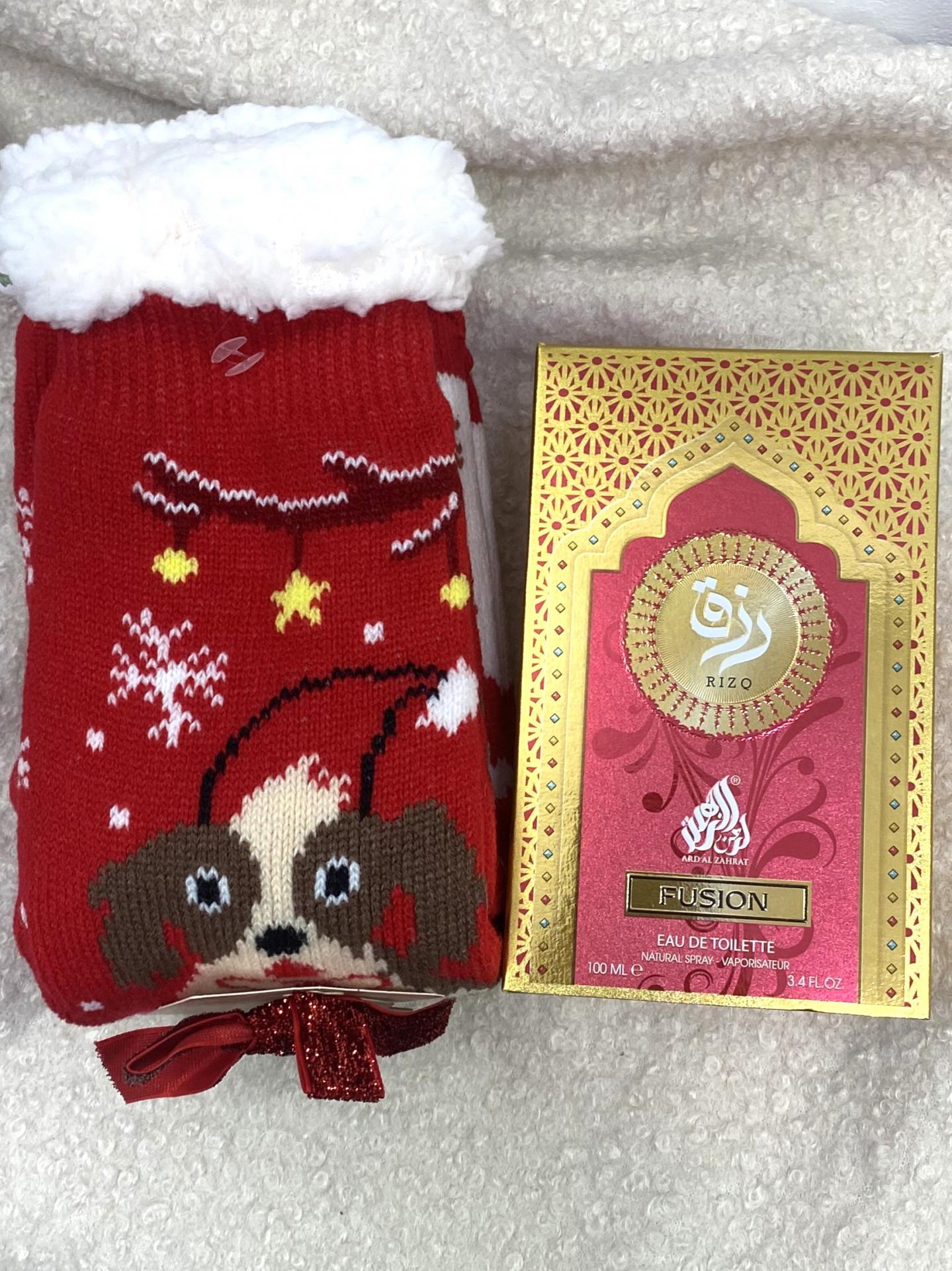 Pack regalo con calcetines navideños antideslizantes y perfume unisex envuelto en bolsa transparente.