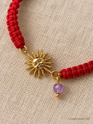 Detalle del sol de acero dorado con rostro y pequeña cuenta lila en pulsera de hilo rojo [2]