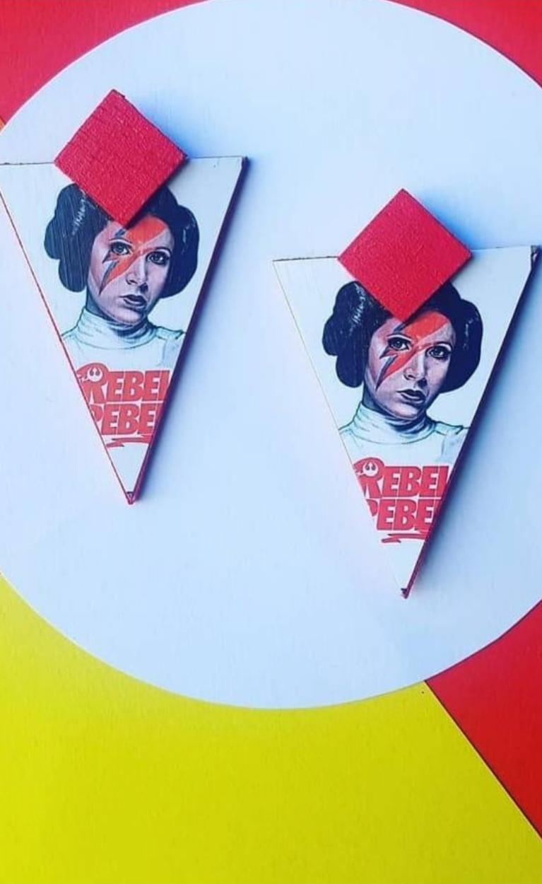 Pendientes de madera con la imagen de Leia de Star Wars y el texto “Rebel Rebel” en inglés, sobre un fondo de colores