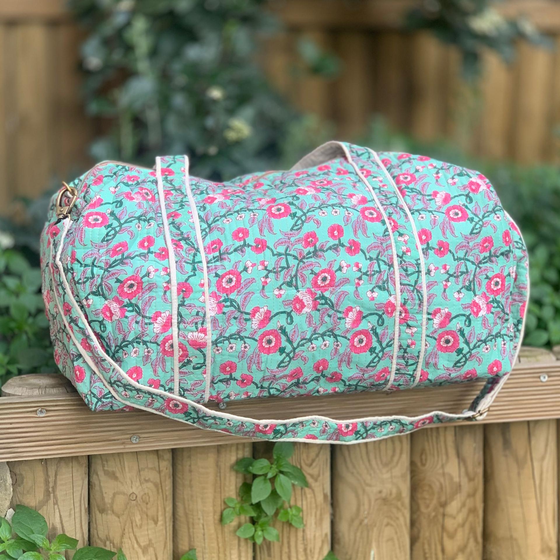 Bolso viaje estampado flores fucsia en fondo azul turquesa