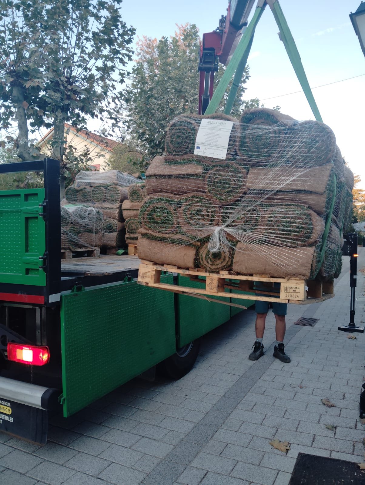 Un camión descarga césped en rollos de tepe para ser instalado por Tecnihabitat en un jardín de Boadilla del Monte