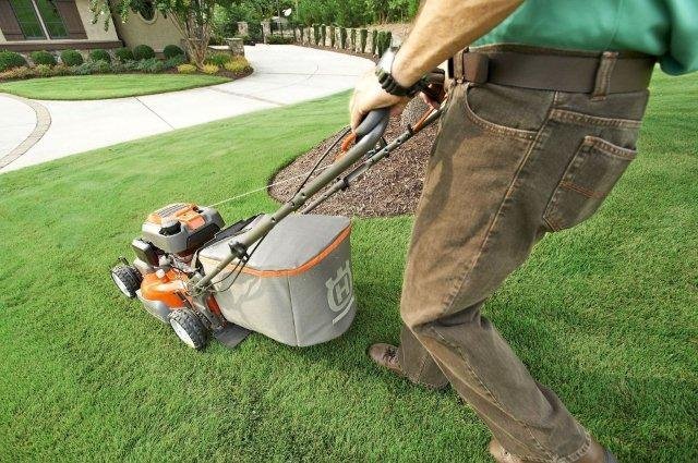 Jardinero de la empresa de Jardinería Tecnihabitat cortando el césped de un jardín con un cortacésped de última generación
