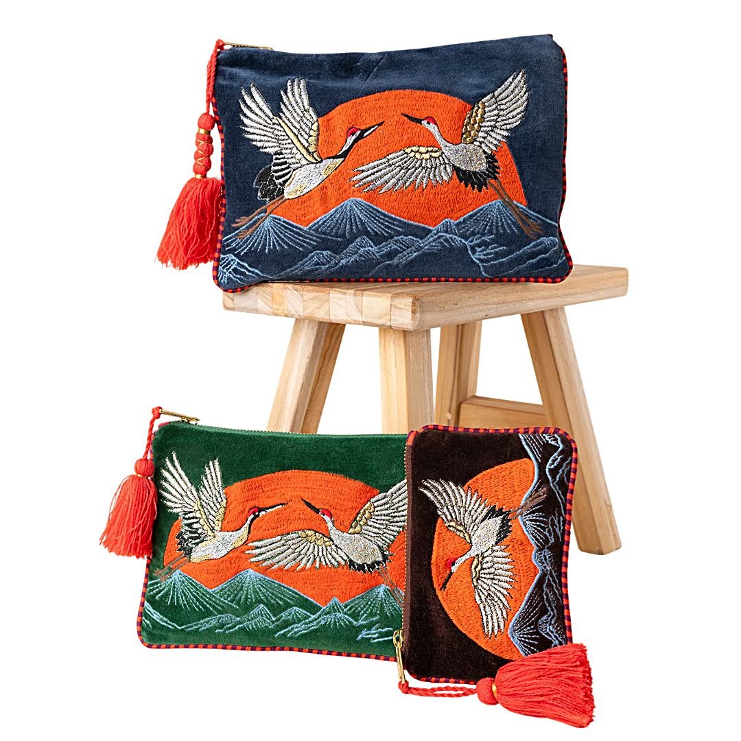 Bolsos de mano Latido con aves y montañas bordadas, fondo naranja y borla roja, en tres tamaños.