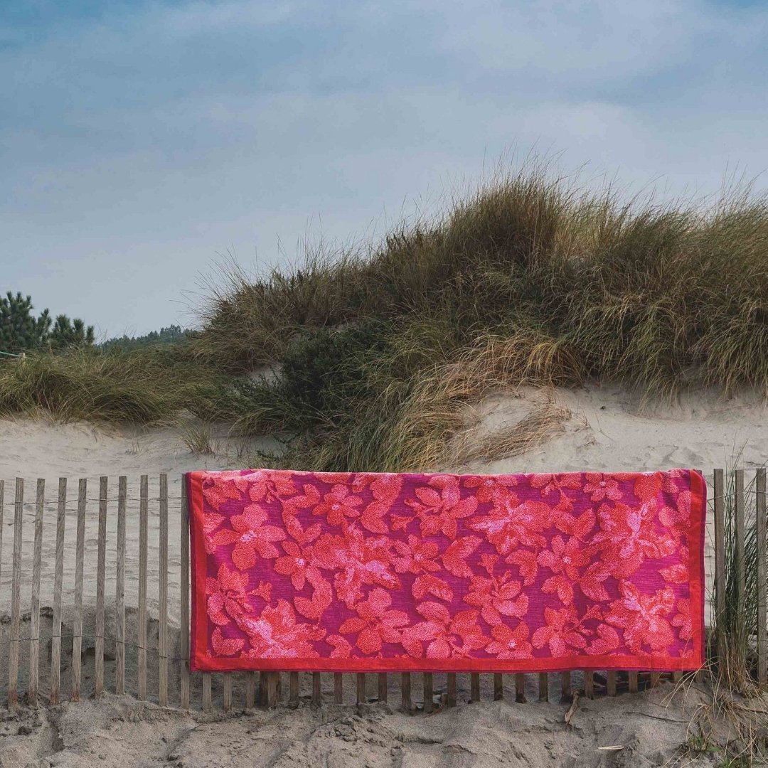 Toalla de playa Lotus 100% algodón 100x180 cm con diseño floral rojo sobre arena
